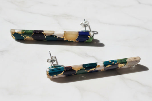 Close-up of multicolor striped bar earrings with gold details