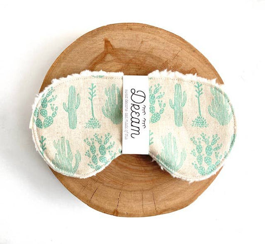Cotton Sleep Mask Saguaro with cactus design displayed on a wooden base, offering a stylish and comfortable sleep accessory.