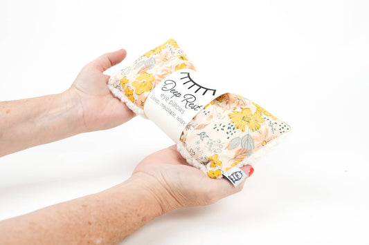 Hands holding Deep Rest Eye Pillow - Relaxation & Sleep Aid, showcasing its soft fabric and floral print for calming self-care use.