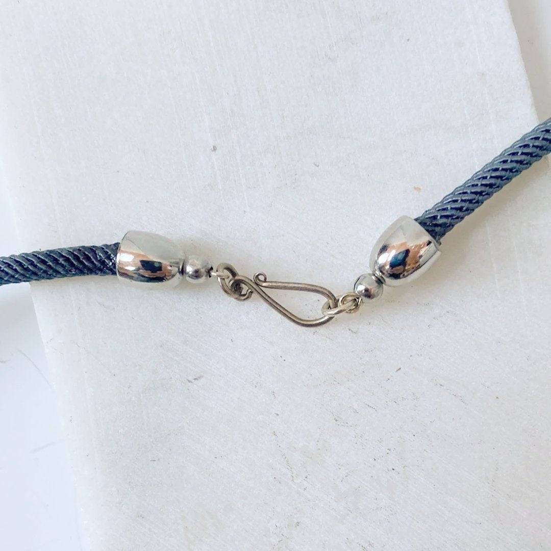 Close-up of Heart and Pearl Charm Necklace-Uni-T clasp showing secure silver hook and end caps on a twisted grey cord. Durable and fashionable closure.