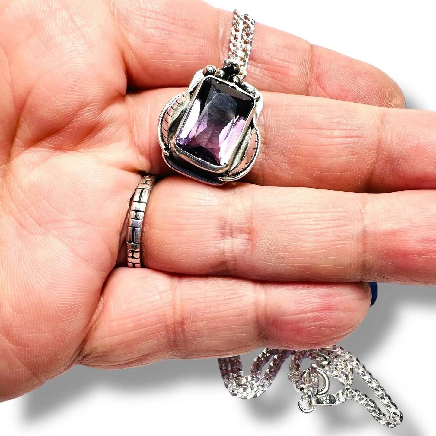 Close-up of Amethyst Grapes Wine Necklace held in hand, highlighting the rich purple gemstone and intricate silver grapevine detailing.