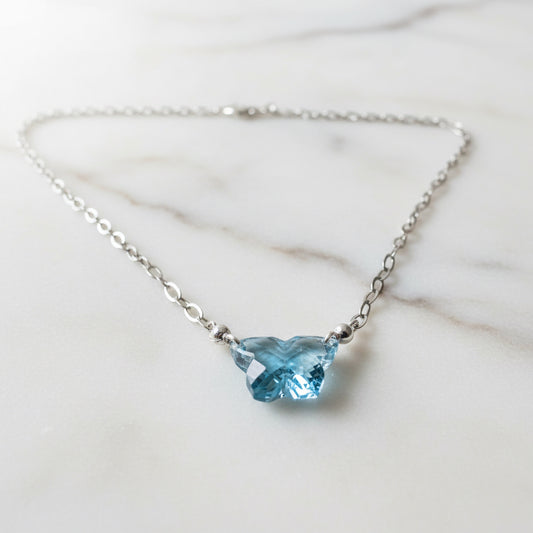 Close-up of butterfly-shaped blue gemstone pendant on silver chain