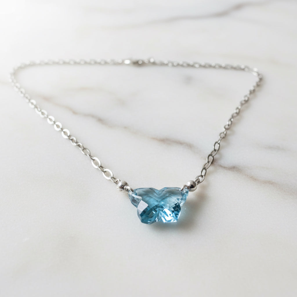 Close-up of butterfly-shaped blue gemstone pendant on silver chain