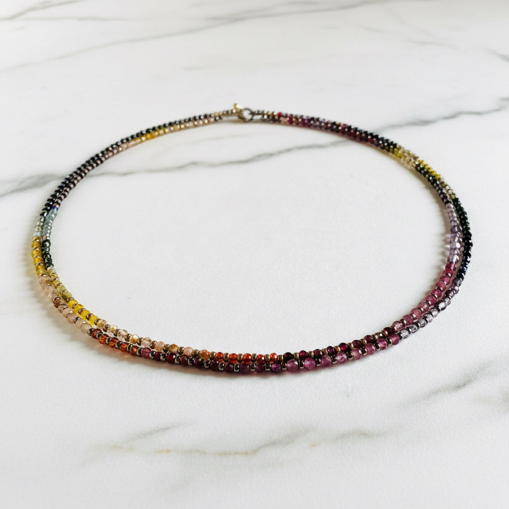 Rainbow gemstone beaded necklace with gold clasp on white background