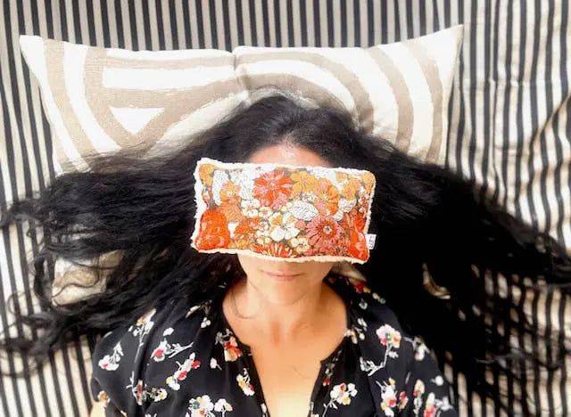 Woman using Deep Rest Eye Pillow during meditation, demonstrating its comfort and effectiveness for deep relaxation and improved sleep.