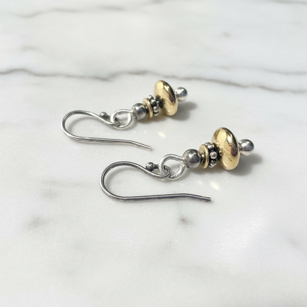 Close-up of sterling silver and gold beaded earrings with black and silver details