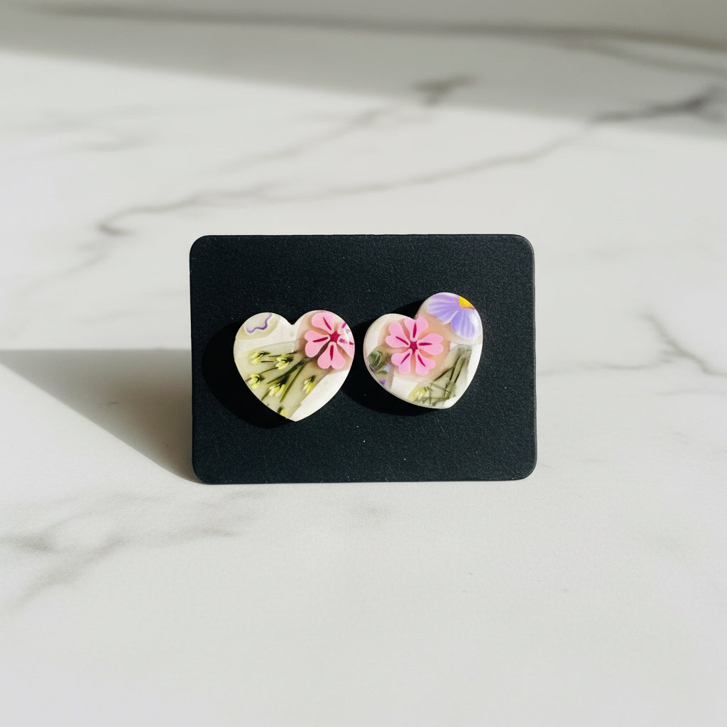 Floral heart-shaped handmade clay stud earrings on black display card