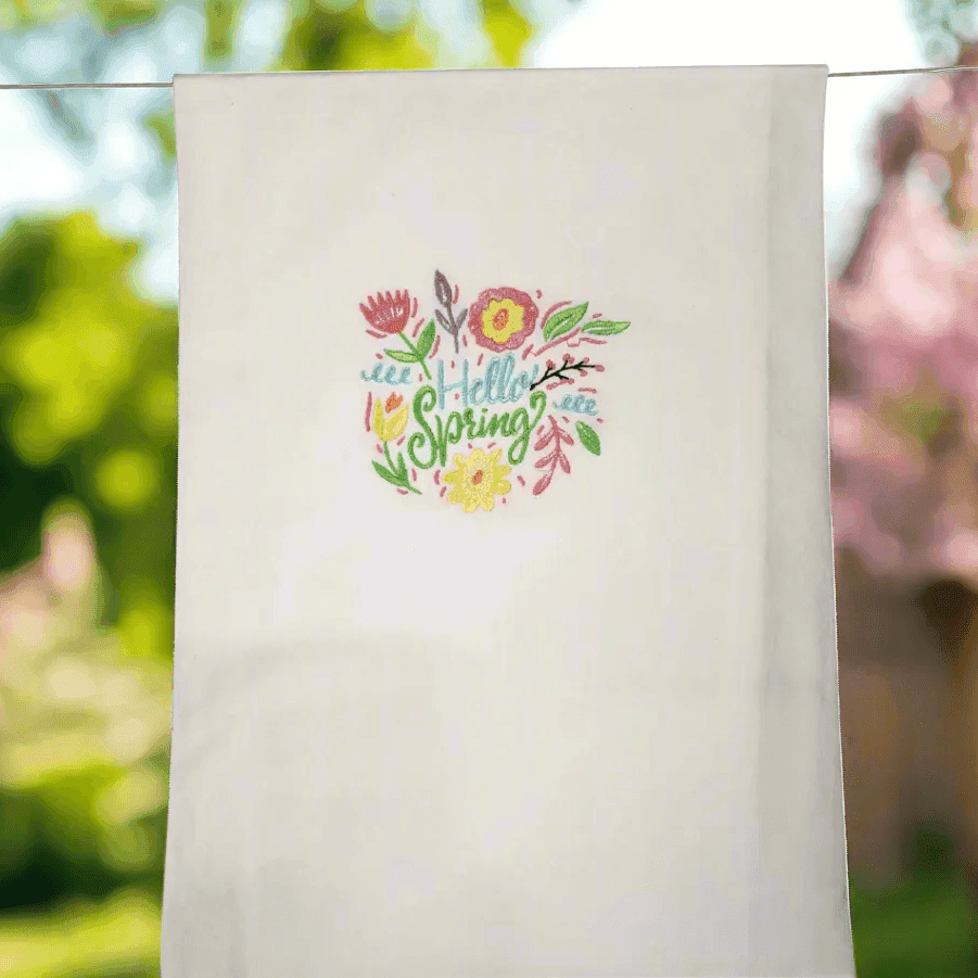 Spring flowers embroidered towel hanging outdoors with colorful floral design. Ideal kitchen towel for brightening home and garden spaces.