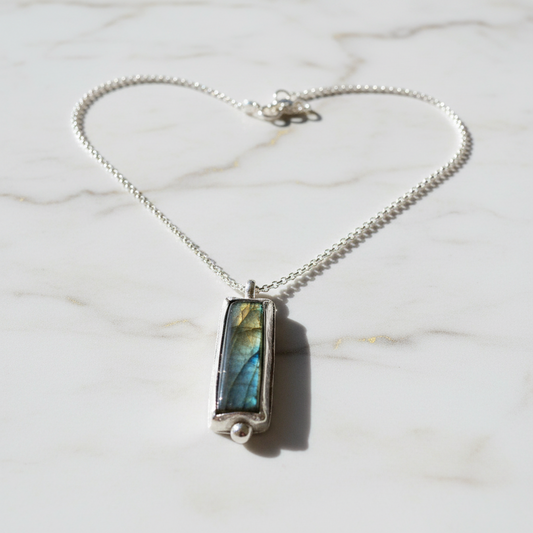 Labradorite pendant necklace with silver chain on marble background