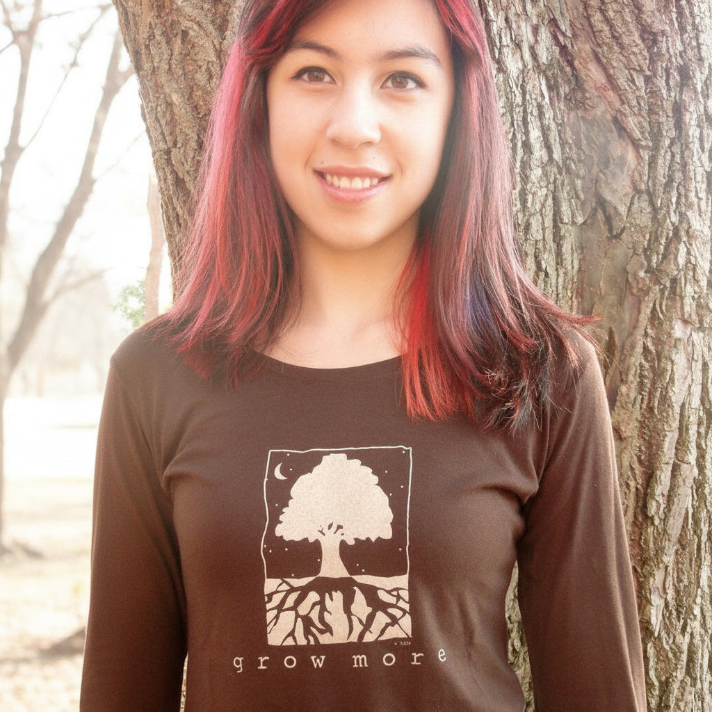 Close-up of woman modeling eco-friendly 'Grow More' tree long sleeve T-shirt in dark brown, made from bamboo and organic cotton blend.
