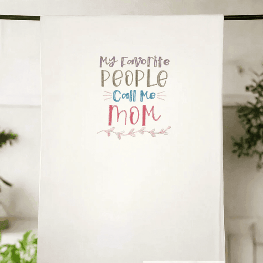 Heartwarming embroidered kitchen towel hanging on display with 'My favorite people call me Mom' design. Perfect Mother's Day or home gift.