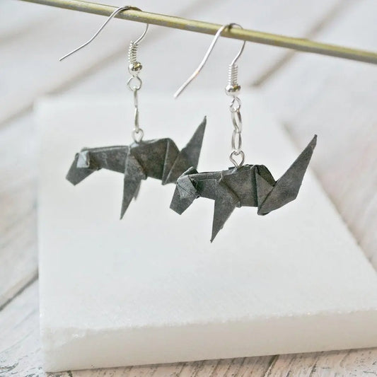 Hanging grey origami dog earrings with intricate paper folds and silver ear wires, showcasing unique paper craft jewelry style.