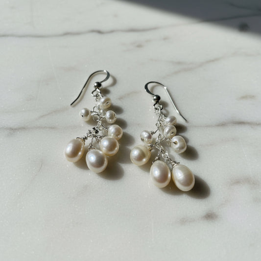 Close-up of pearl drop earrings with silver hooks