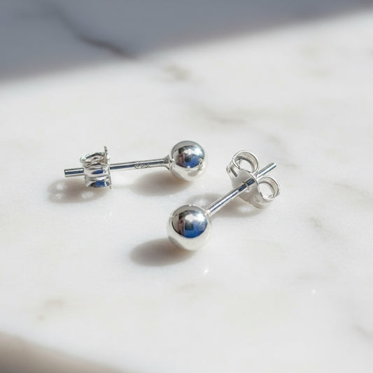 Silver stud earrings on marble surface