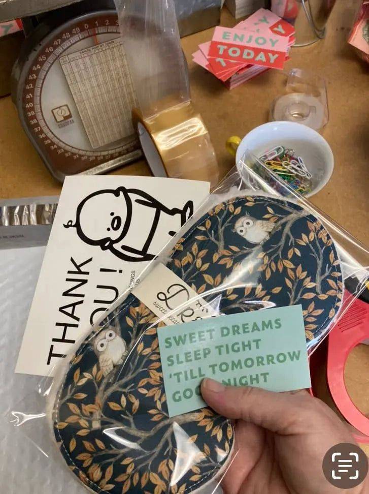 Packaged cotton sleep mask for relaxation with owl print, shown with thank-you card and sticker. Ideal for gifting and sleep support.
