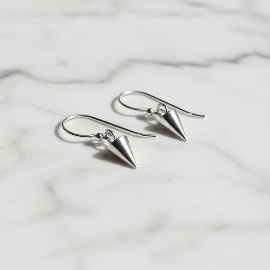 Close-up of silver spike earrings on white marble background
