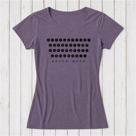 Purple women's T-shirt with black graphic print of a vintage typewriter keyboard and the phrase write more, made from soft organic cotton, laid on white wooden background
