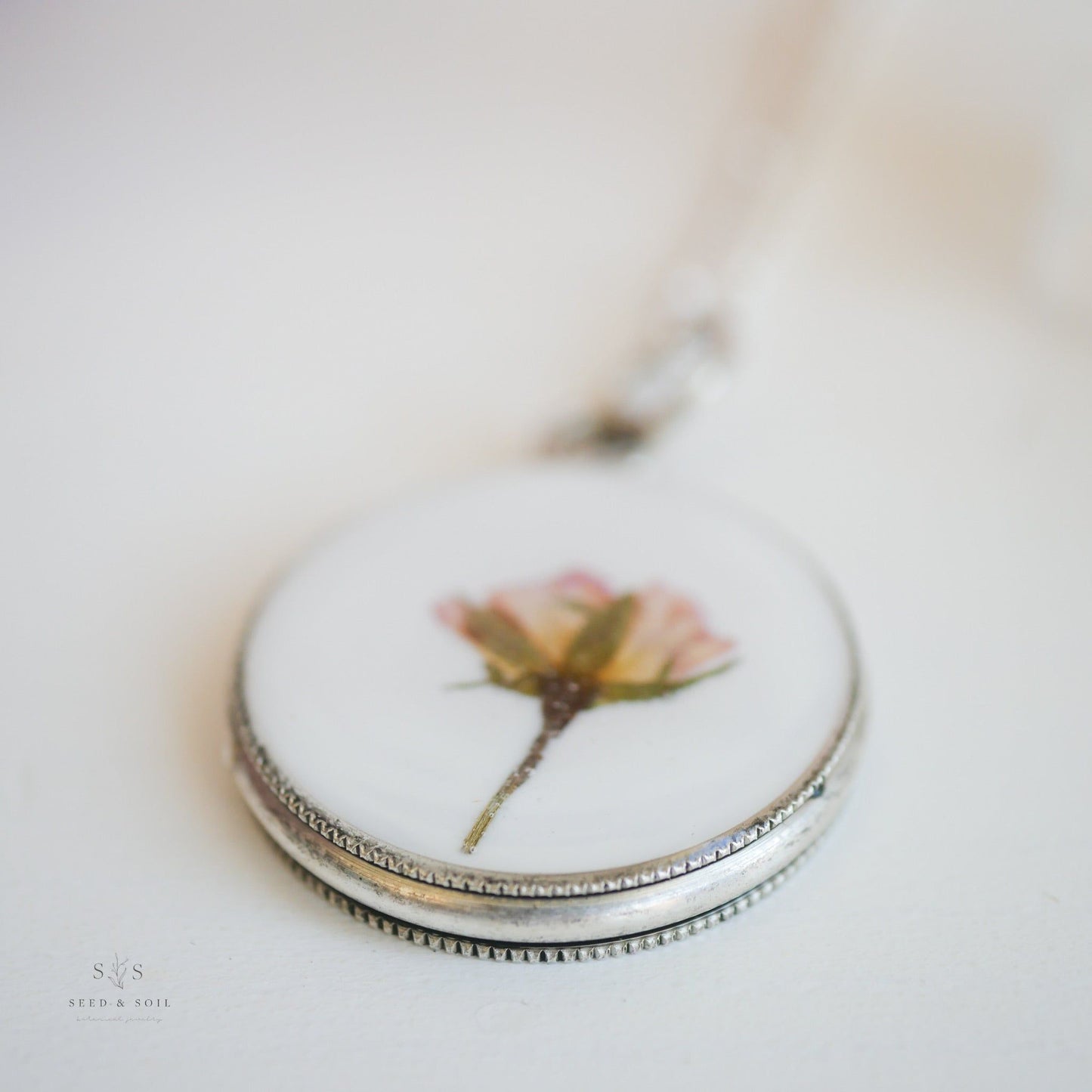 Macro shot of silver Valentine Round Rose Necklace pendant featuring a preserved rose, ideal for romantic and nature-inspired jewelry.