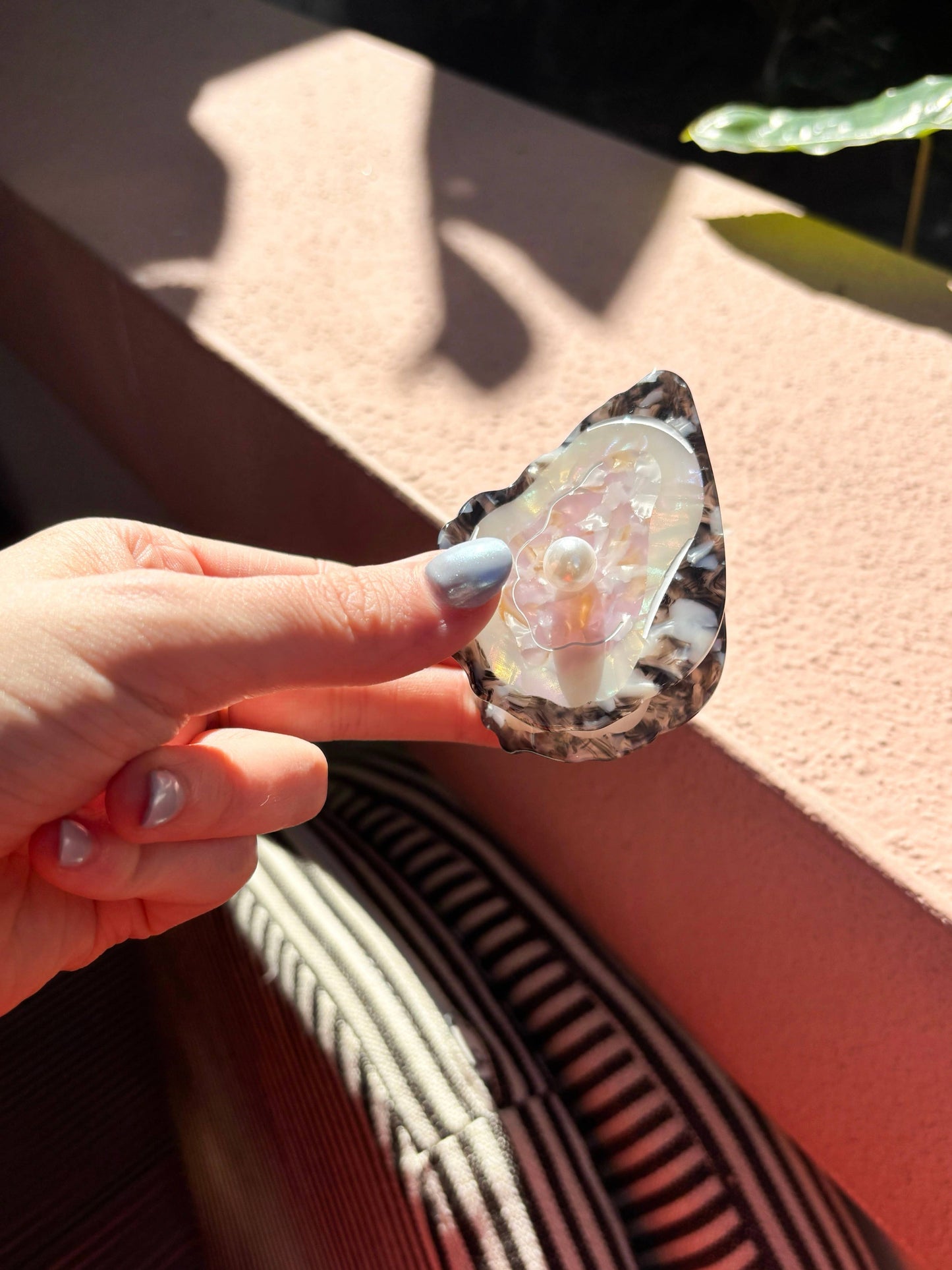 Line&Co Oyster Claw Clip with Pearl held in hand under natural light. Stylish hair accessory with realistic oyster shell look.