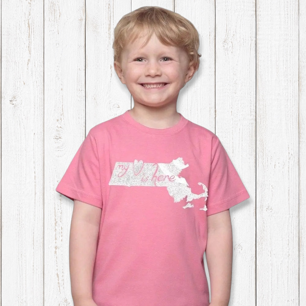 A smiling child wearing a pink Uni-T organic cotton t-shirt featuring a white Massachusetts map and heart graphic.
