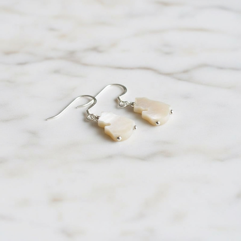 Close-up of Mother of Pearl Kitty earrings on marble background