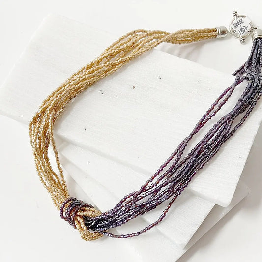 Blue Metallic Beaded Two Tone Knot Necklace with silver clasp, combining gold and burgundy beads in a twisted knot for a bold statement look.