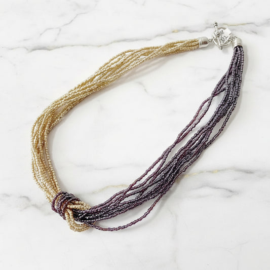 Blue Metallic Beaded Two Tone Knot Necklace with silver clasp, combining gold and burgundy beads in a twisted knot for a bold statement look.