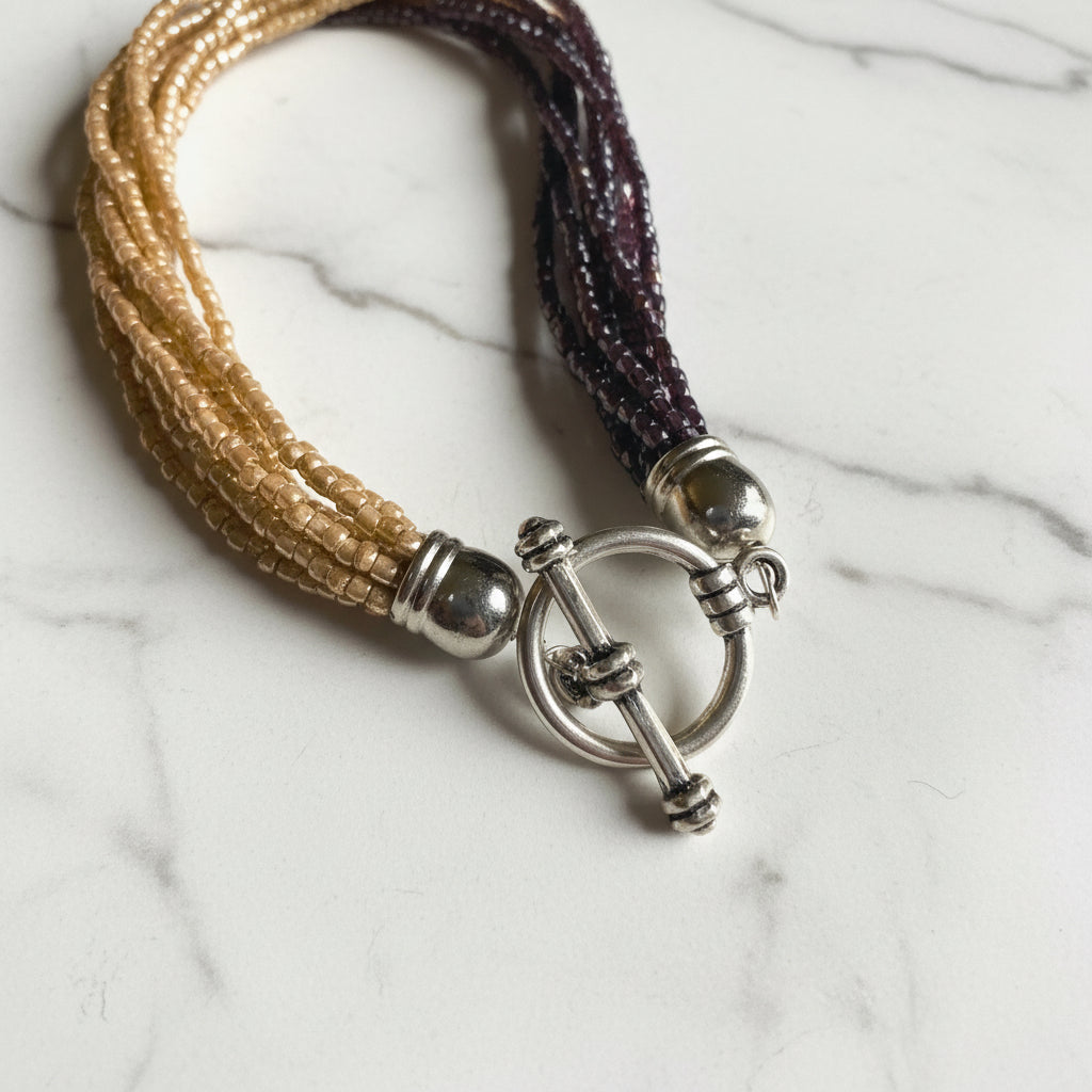 Toggle clasp of the Beaded Two Tone Knot Necklace with silver-plated finish, securing multi-strand golden and burgundy beaded necklace.