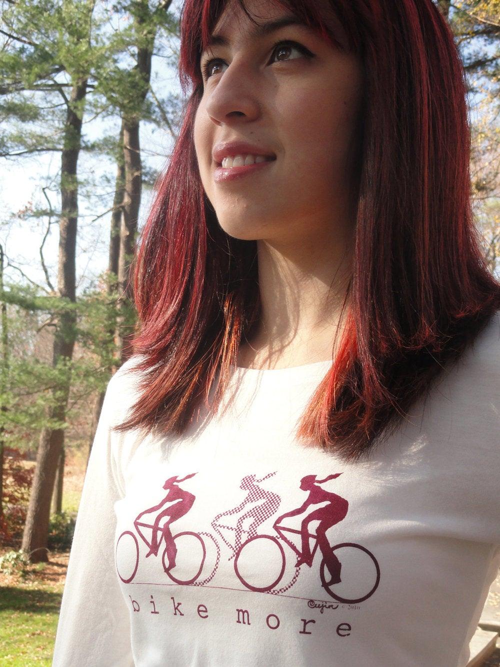 Close-up of model in cream bamboo and organic cotton Women's Bicycle Long Sleeve T-Shirt with maroon 'Bike More' cycling graphic.