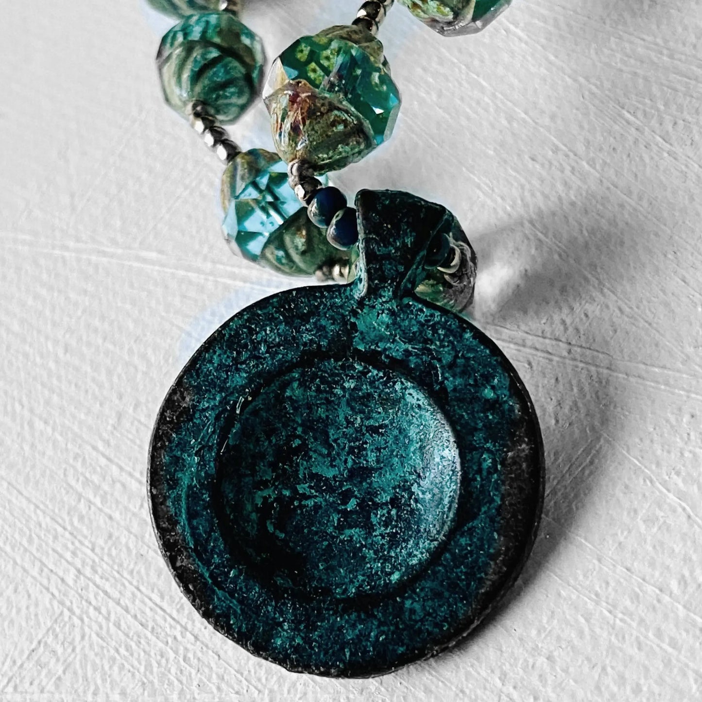 Close-up of Celestial Necklace - Sun Moon Pendant Set showcasing the textured antique brass back of the pendant and vibrant glass beads.