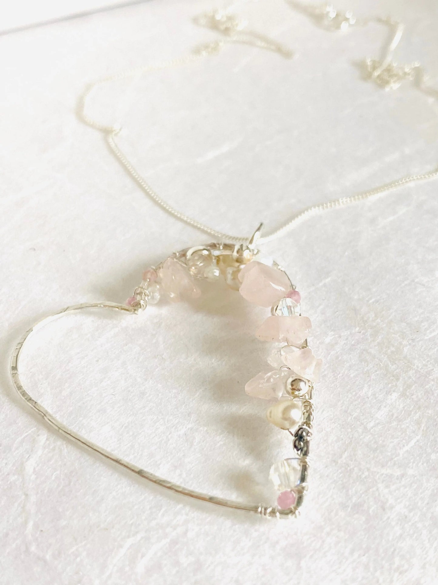 Detailed view of silver Crystal Heart Necklace with rose quartz and pearl embellishments. Elegant handcrafted gemstone jewelry piece.