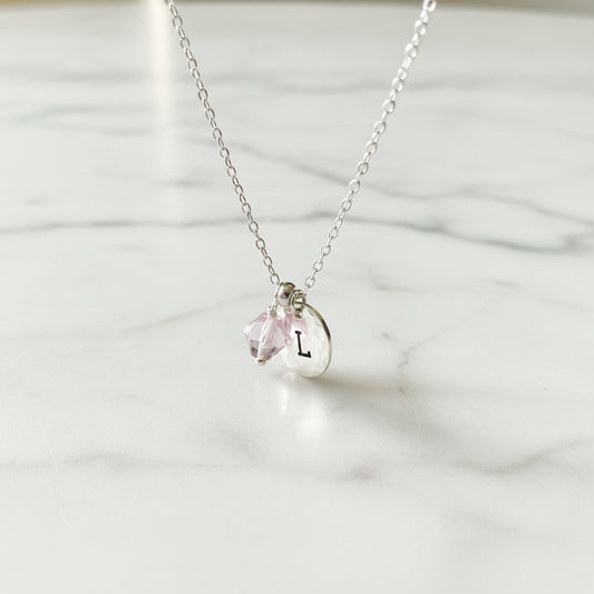 Personalized Initial Necklace featuring silver chain, pink crystal charm, and hammered disc with letter 'L'. Ideal custom gift accessory.