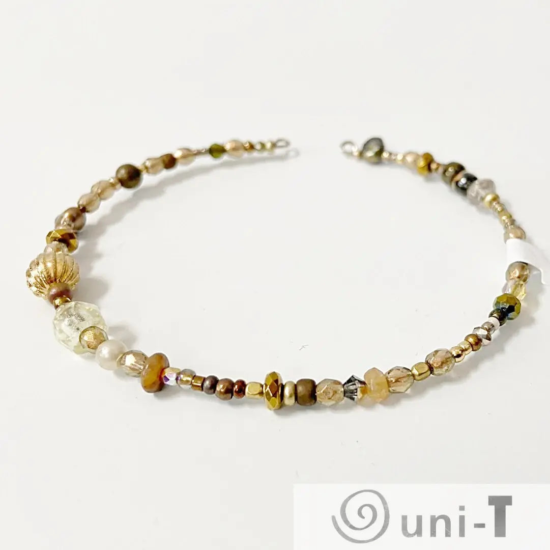 Stylish beaded cuff bracelet with gold and bronze beads, including faceted and round designs. Perfect jewelry piece for modern fashion.