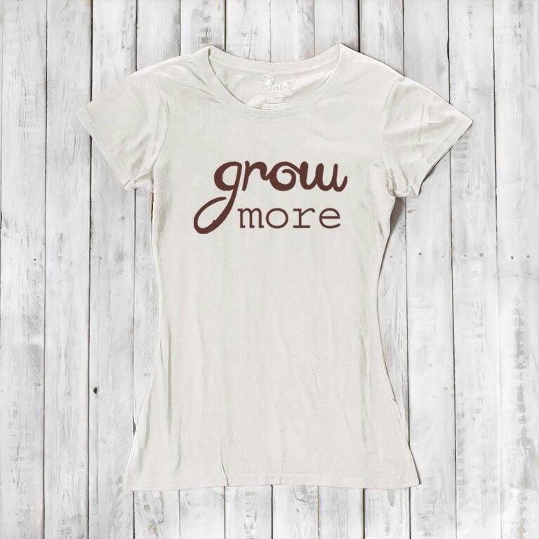 Cream-colored women's T-shirt with brown 'Grow More' typography. Eco-friendly bamboo and organic cotton tee for gardening lovers.