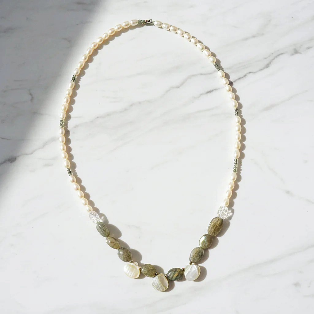 Full view of labradorite and pearl necklace with sterling silver clasp laid flat on a grey surface, highlighting gemstone textures.