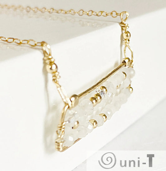 Close-up of Moonstone Bar Necklace with gold-filled wire and shimmering moonstone beads. Unique handcrafted accessory with quartz bead accents.