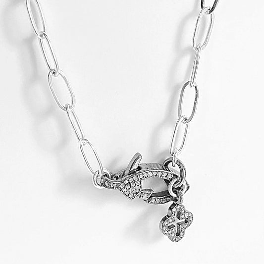 Close-up of moonstone clasp on sterling silver paperclip chain necklace, showcasing pave detailing and dangling antiqued charm.