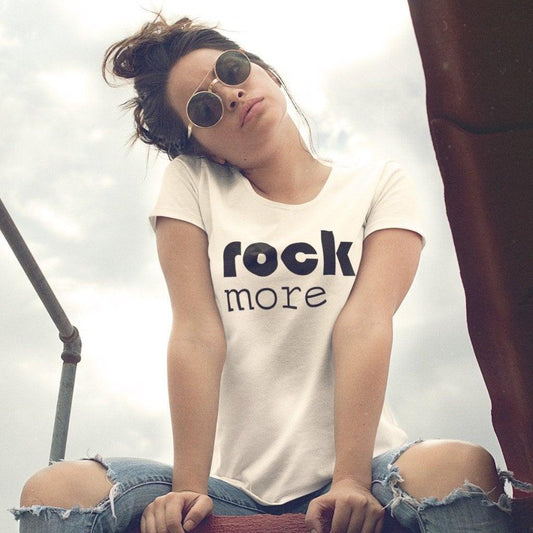 Model wearing white 'Rock More' women's bamboo & organic cotton t-shirt styled with ripped jeans. Sustainable music-themed tee for concerts.