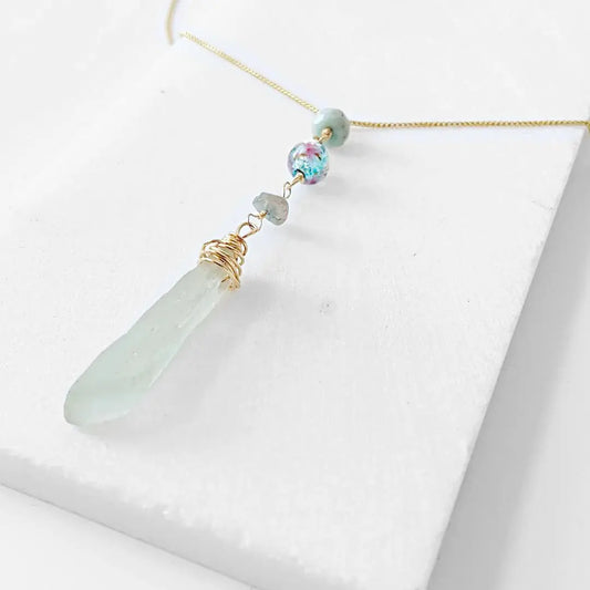 Close-up of Handmade Sea Glass Necklace featuring wire wrapped sea glass pendant, Murano floral bead, and tourmaline accents on a delicate gold chain.