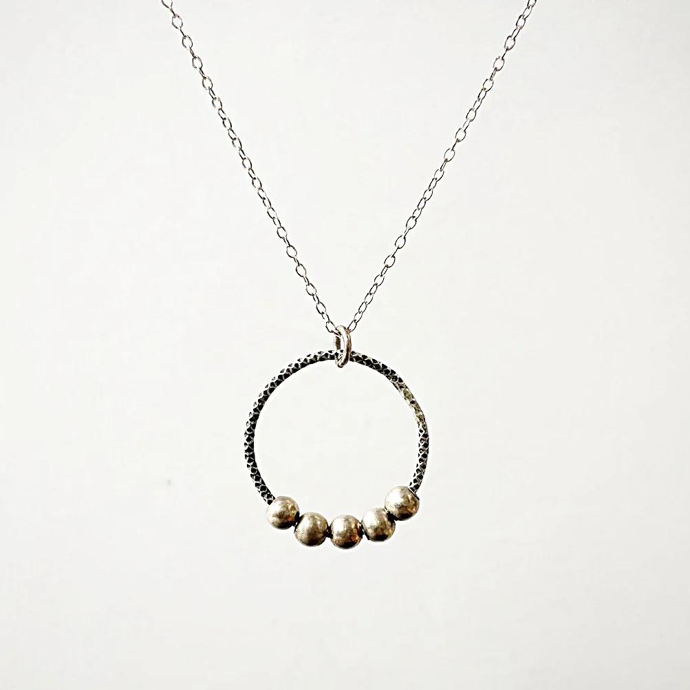 Circle Fidget Necklace from the Circle Fidget Jewelry Set, showcasing a hammered circle pendant with five silver beads on a delicate chain.