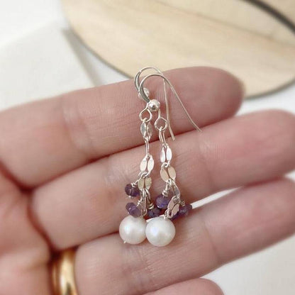 Handcrafted sterling silver earrings with cultured pearls and amethyst gemstones, shown held in hand for size reference. Elegant and delicate design.