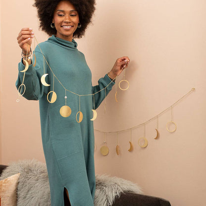 Woman displaying celestial brass garland with moon phases, perfect for wall decor in home and garden artwork collection.