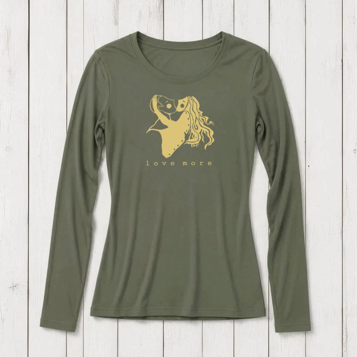 Long sleeve women's graphic t-shirt in olive green with a romantic heart and girl illustration, featuring the words love more, on a white wooden background