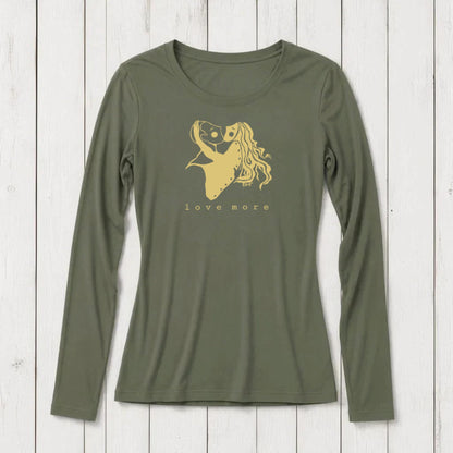 Long sleeve women's graphic t-shirt in olive green with a romantic heart and girl illustration, featuring the words love more, on a white wooden background