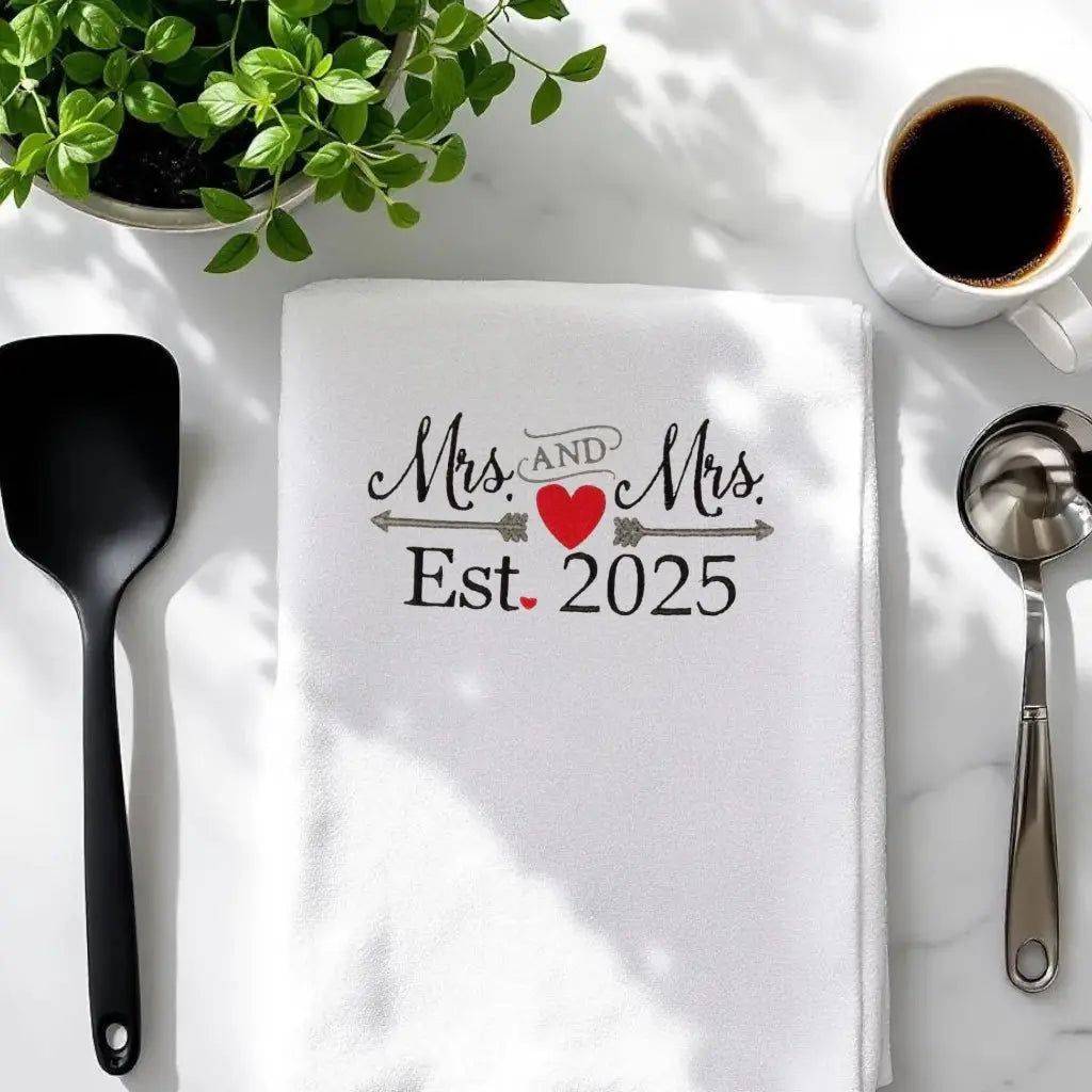 2025 Mrs & Mrs Towel - Embroidered flour sack towel folded on counter, ideal for gifting or adding charm to kitchen or bathroom spaces.