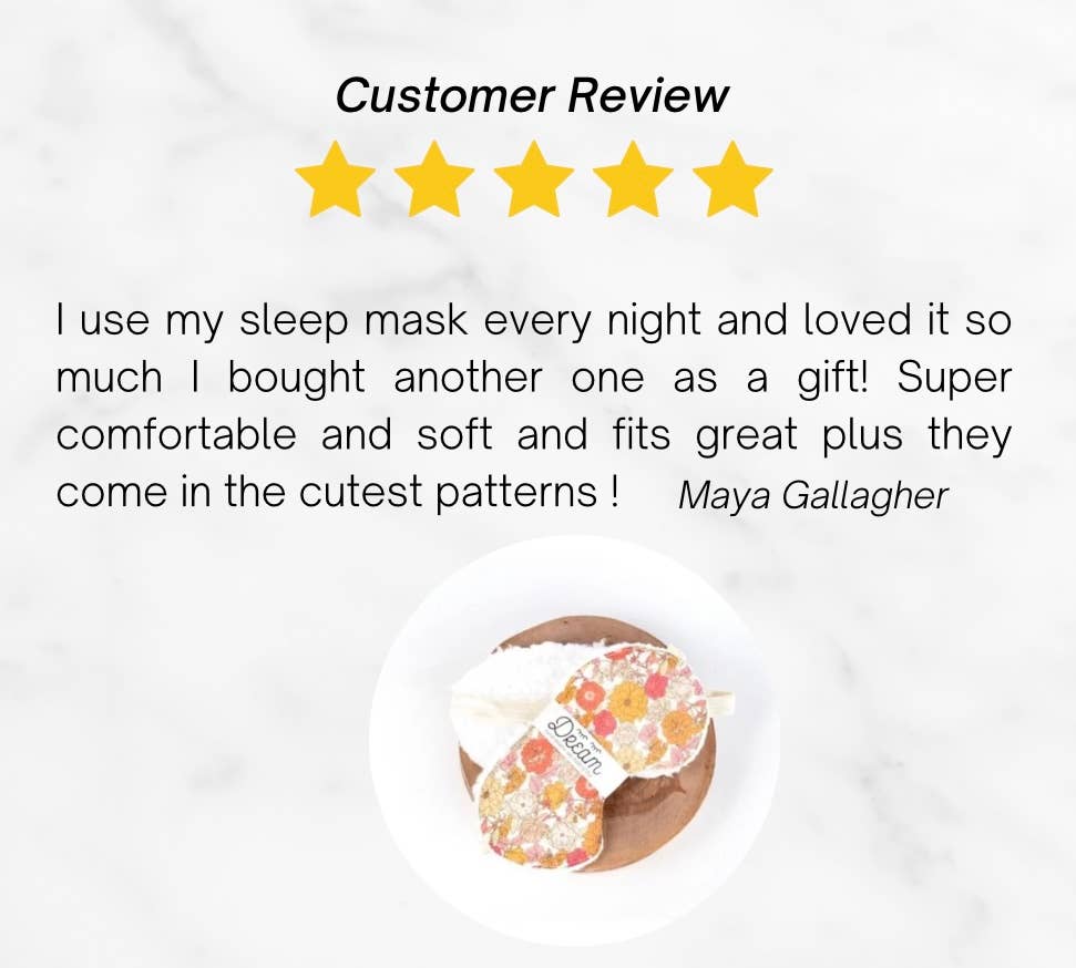 Customer review with 5-star rating praising the cotton sleep mask’s comfort and cute patterns. Features floral sleep mask on wooden tray.