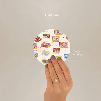 Hand holding Seedlings Coaster by Matchbooks showing foil details and cork backing, ideal for stylish barware protection.