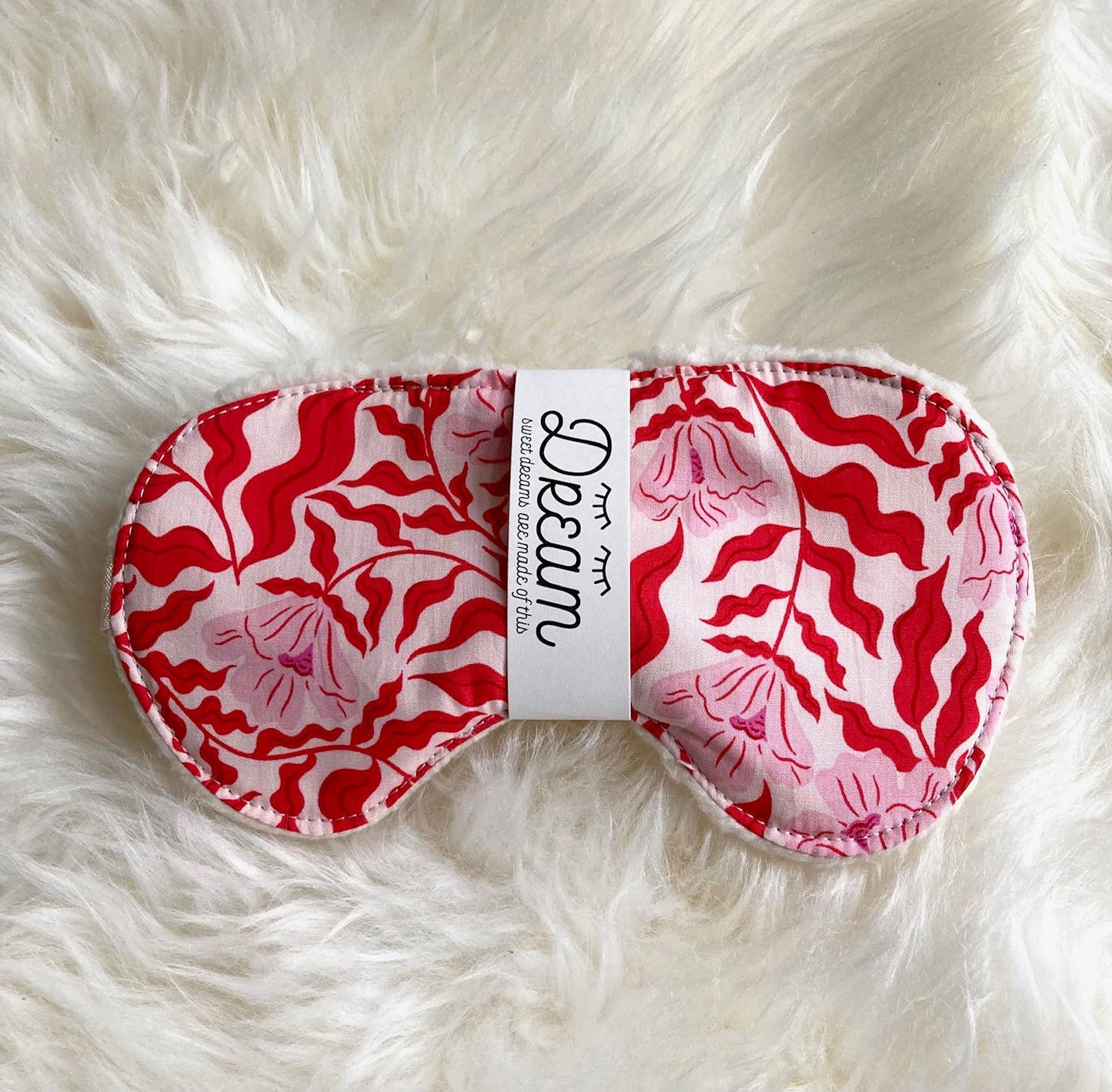 Sweet Dreams Sleep Mask - Red Vine Edition with vibrant red vine pattern on cotton, shown on a fluffy white surface for a cozy, relaxing vibe.