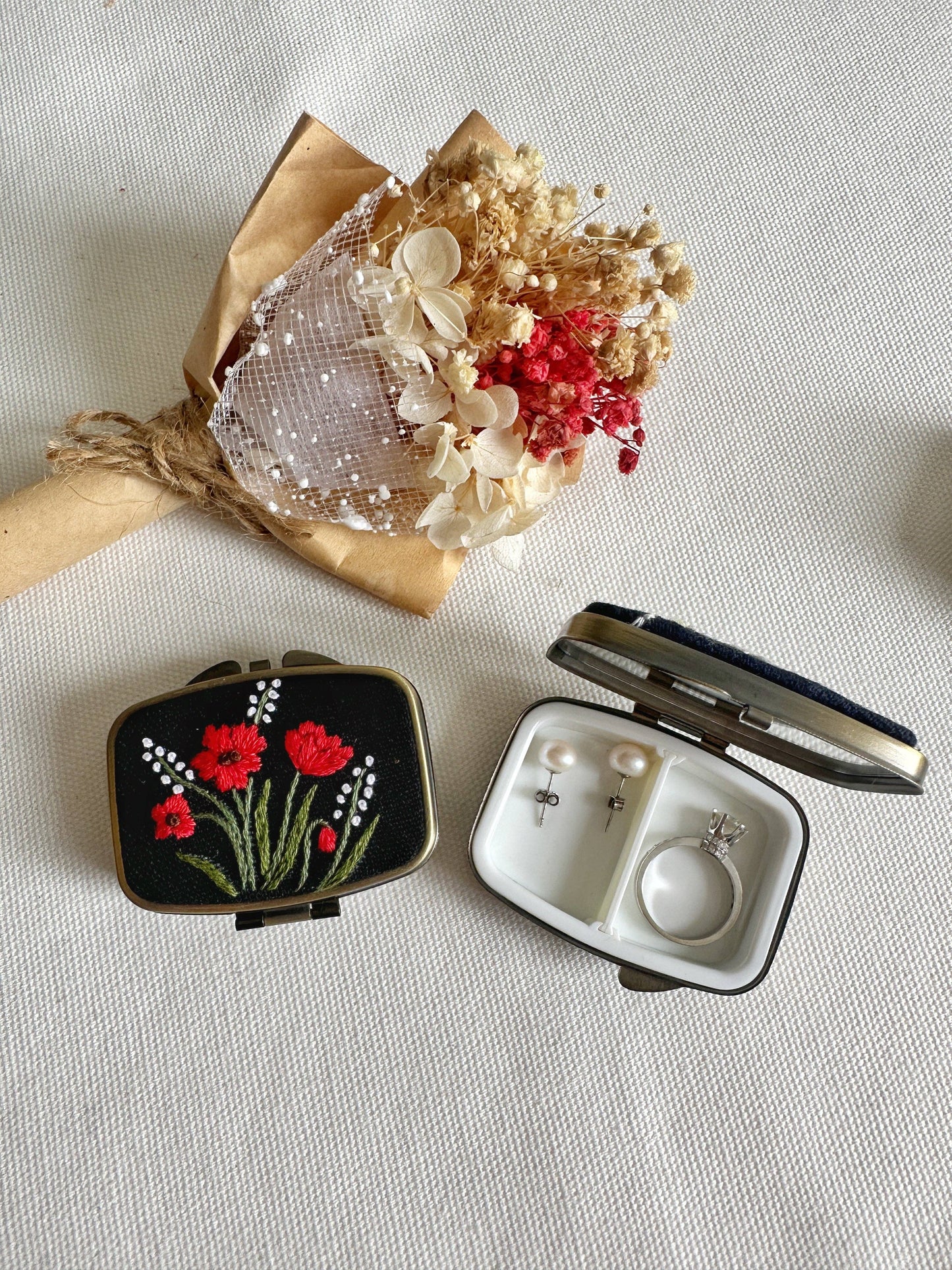 Black Floral Embroidered Jewelry Box - Elegant Storage with red poppy design, open to show interior ring and earring compartments next to dried flowers.