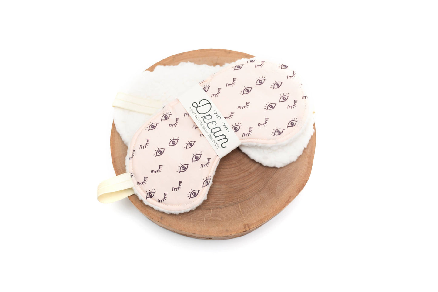 Wink Sweet Dreams Cotton Sleep Mask with eye pattern and soft cream minky backing, displayed on a wooden tray for home relaxation use.